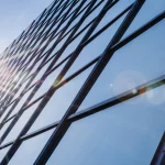 Transparent photovoltaic windows on a glass skyscraper reflecting blue sky and clouds