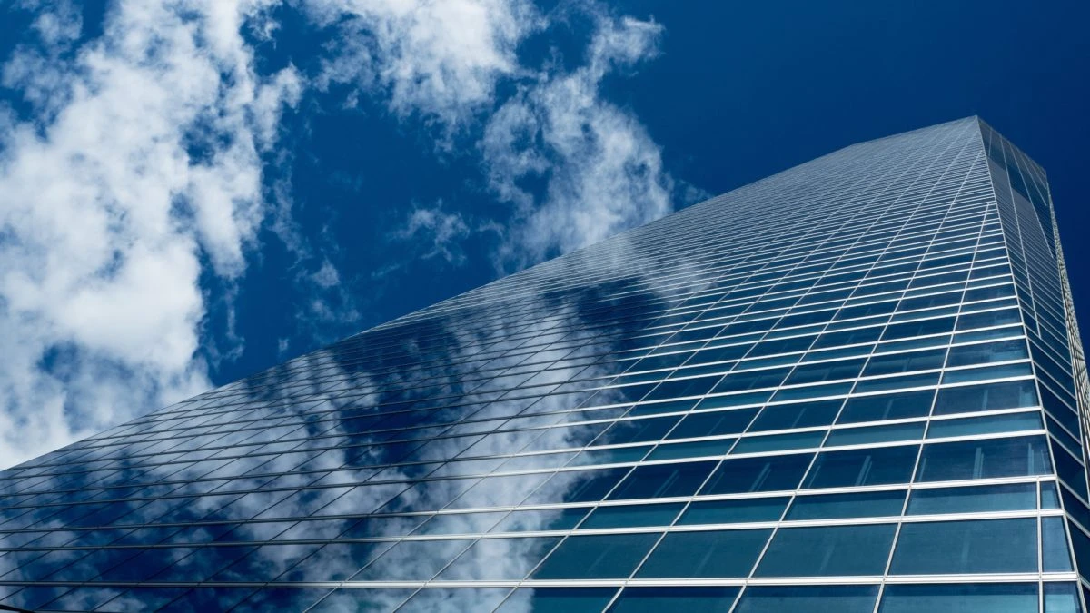 Glass skyscraper facade reflecting sky, ideal surface for photovoltaic windows