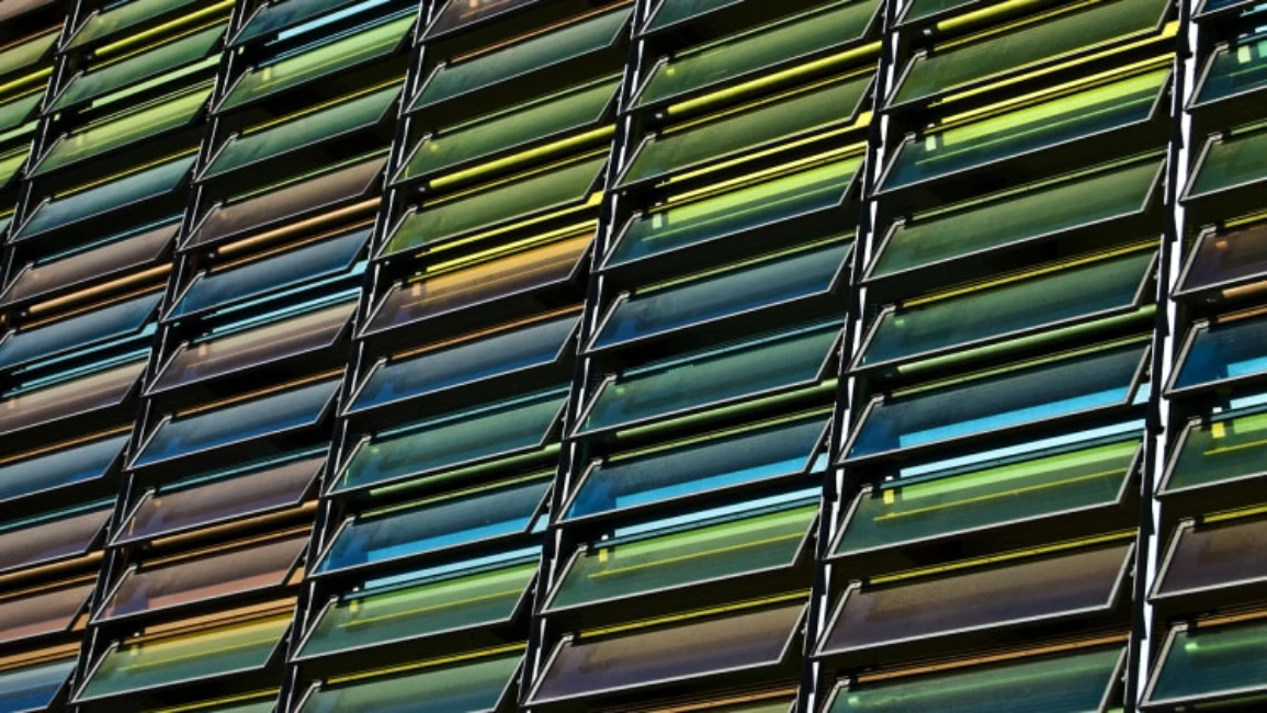 Colorful photovoltaic louver screens on modern façade harvesting solar energy and shading interior